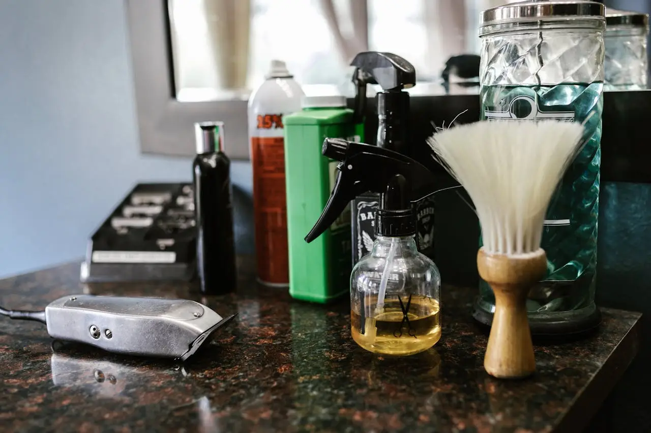 home-img Close-up of barber tools on counter including clippers, spray bottle, and brush in a stylish barbershop.